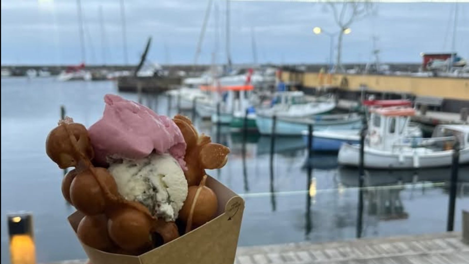 En bubblewaffle med to kugler is foran havnen i aftenlys